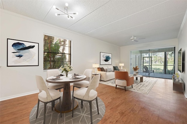 dining area with crown molding, ceiling fan with notable chandelier, a textured ceiling, and hardwood / wood-style flooring