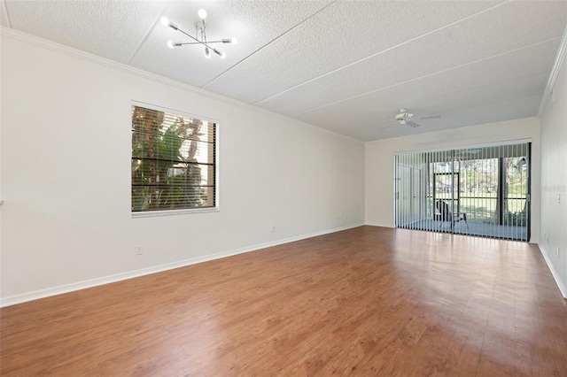 spare room with hardwood / wood-style floors, ceiling fan with notable chandelier, ornamental molding, and a textured ceiling