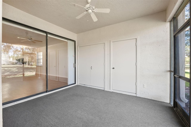 unfurnished bedroom featuring ceiling fan, dark carpet, a textured ceiling, and a closet