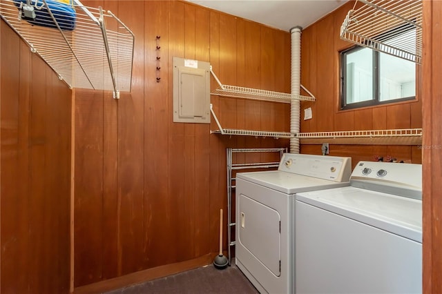 laundry room with independent washer and dryer, electric panel, and wood walls