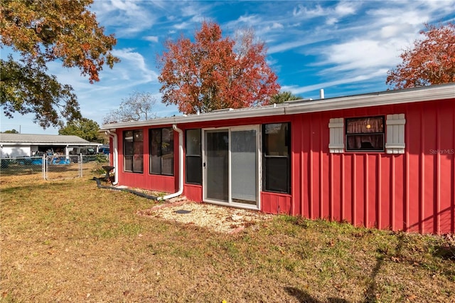 rear view of property featuring a sunroom and a yard