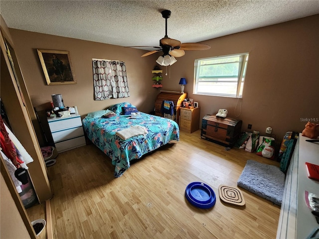 bedroom with hardwood / wood-style flooring, ceiling fan, and a textured ceiling