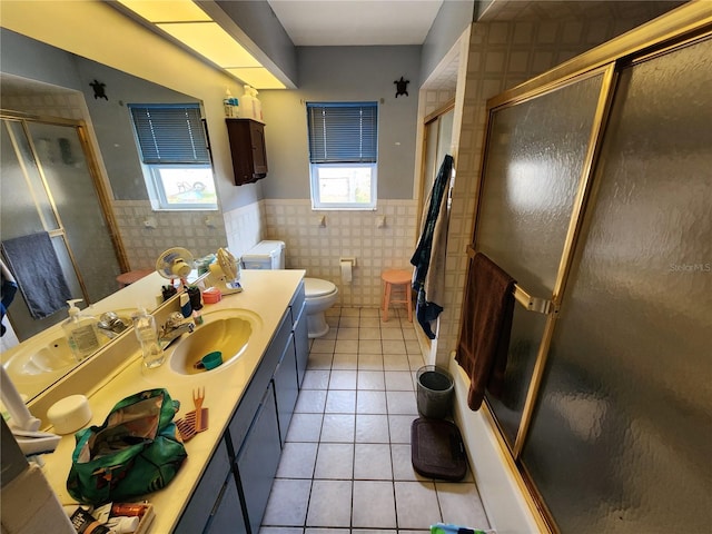 bathroom featuring tile patterned floors, a shower with door, vanity, and tile walls