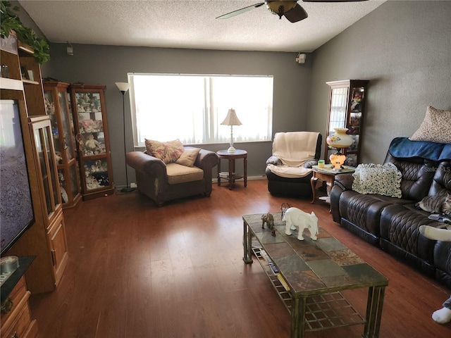 living area with lofted ceiling, ceiling fan, a textured ceiling, and dark wood-type flooring