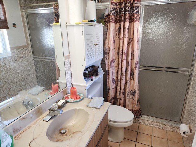 bathroom featuring toilet, a shower stall, vanity, and tile patterned floors