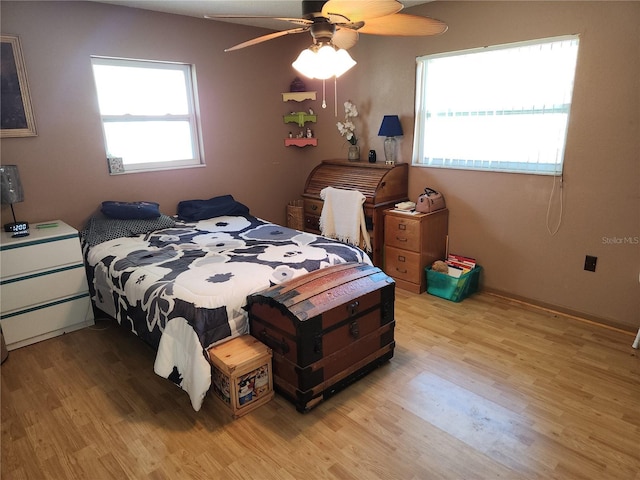 bedroom featuring multiple windows, ceiling fan, and light wood-style flooring