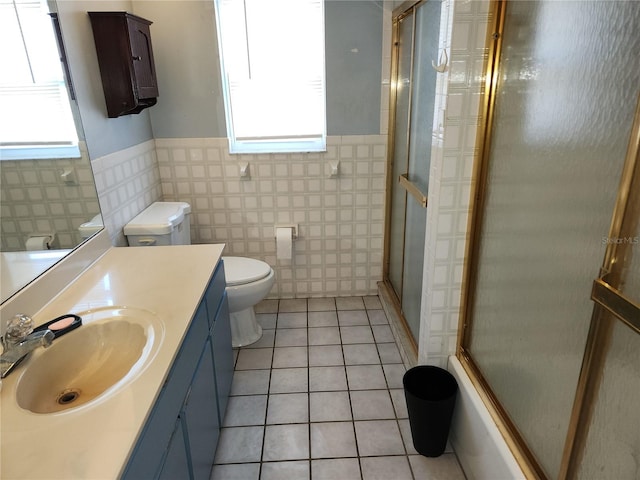 full bathroom featuring tile patterned flooring, toilet, a shower with shower door, a wainscoted wall, and vanity