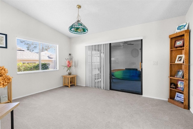 empty room with a textured ceiling, carpet floors, vaulted ceiling, and ceiling fan