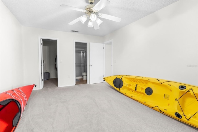 bedroom with ceiling fan, ensuite bathroom, a walk in closet, light carpet, and a closet