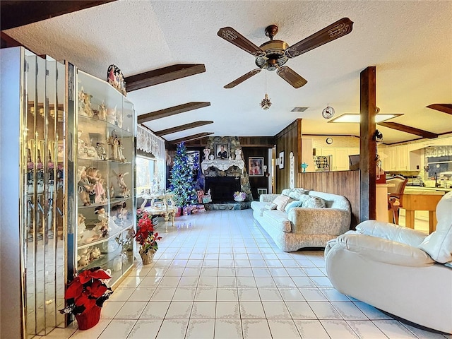 tiled living room featuring ceiling fan, vaulted ceiling with beams, a textured ceiling, wooden walls, and a fireplace