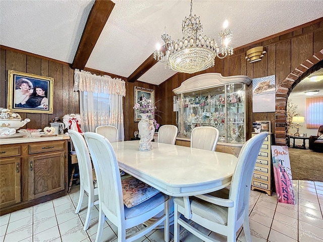 tiled dining area with lofted ceiling with beams, wood walls, a textured ceiling, and a chandelier