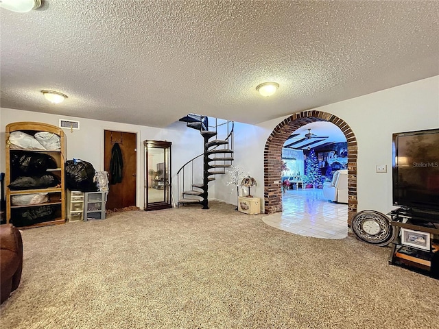 living room featuring carpet flooring, ceiling fan, and a textured ceiling