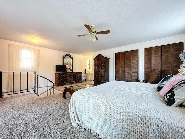 carpeted bedroom featuring ceiling fan, a textured ceiling, and multiple closets