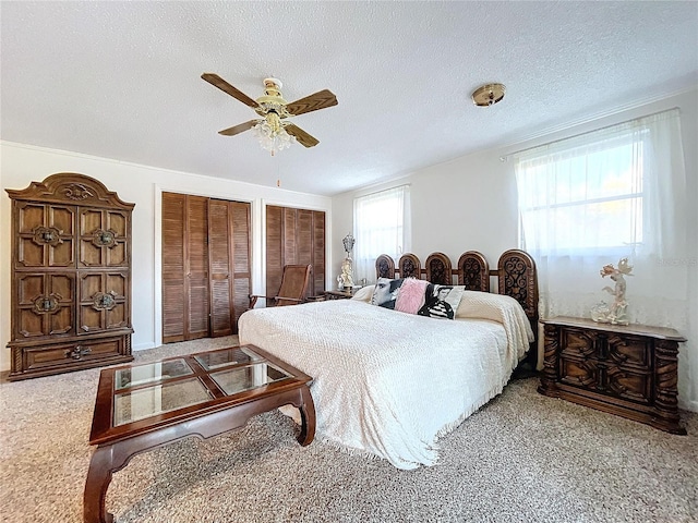 bedroom featuring multiple windows, a textured ceiling, ceiling fan, and carpet flooring