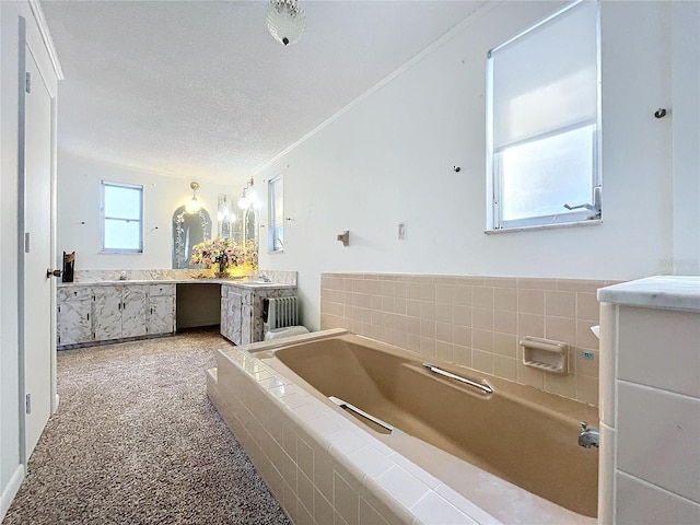 bathroom featuring tiled tub, vanity, a textured ceiling, and ornamental molding