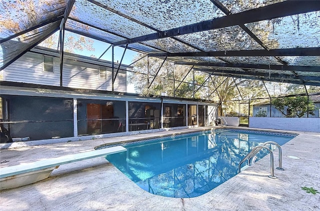 view of pool featuring glass enclosure, a diving board, and a patio