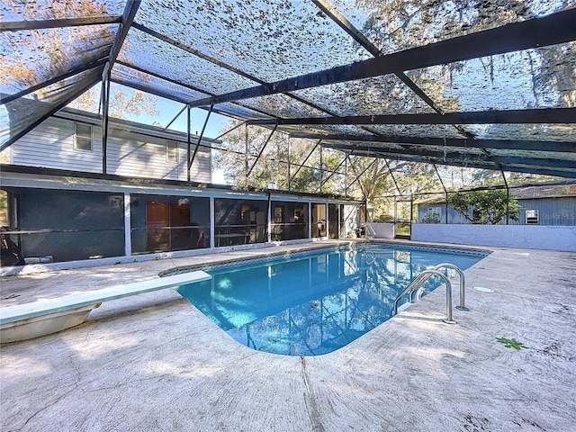 view of swimming pool featuring glass enclosure, a diving board, and a patio