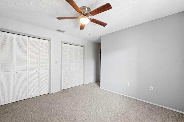 unfurnished bedroom with ceiling fan, light carpet, and multiple closets