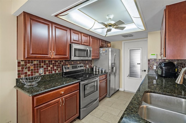 kitchen featuring dark stone countertops, light tile patterned floors, sink, and appliances with stainless steel finishes