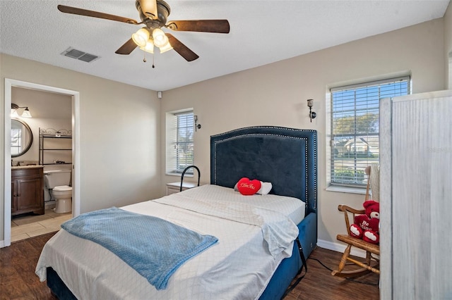 bedroom featuring multiple windows, ceiling fan, ensuite bathroom, and hardwood / wood-style flooring