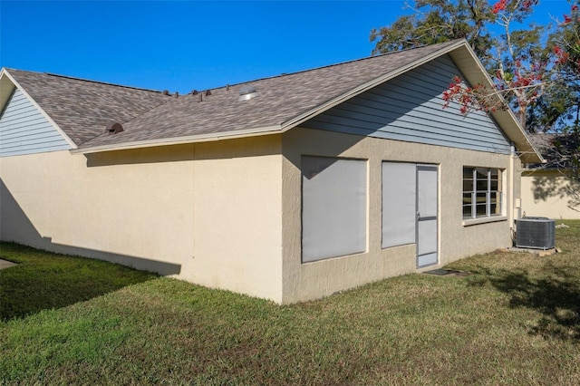 view of side of property with central AC and a yard