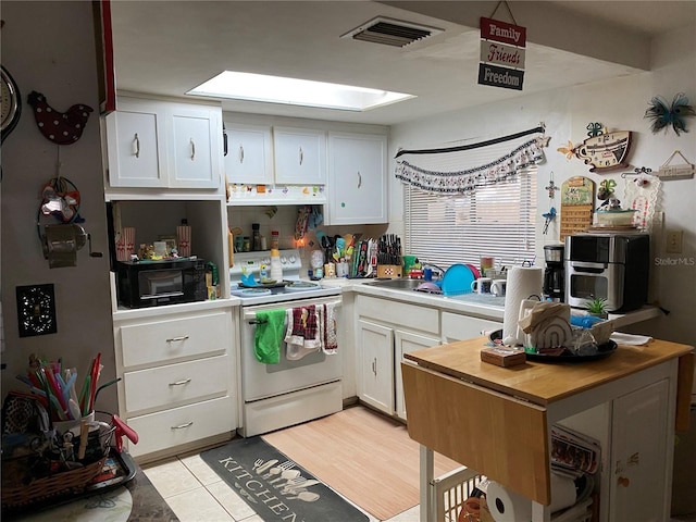 kitchen featuring premium range hood, a skylight, white cabinets, and white electric range oven