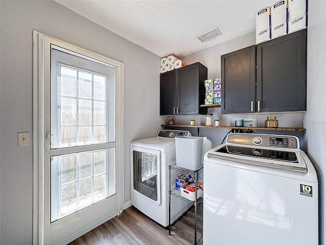 washroom featuring a textured ceiling, cabinets, separate washer and dryer, and plenty of natural light