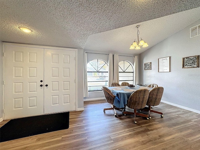 dining area featuring a textured ceiling, an inviting chandelier, lofted ceiling, and hardwood / wood-style flooring