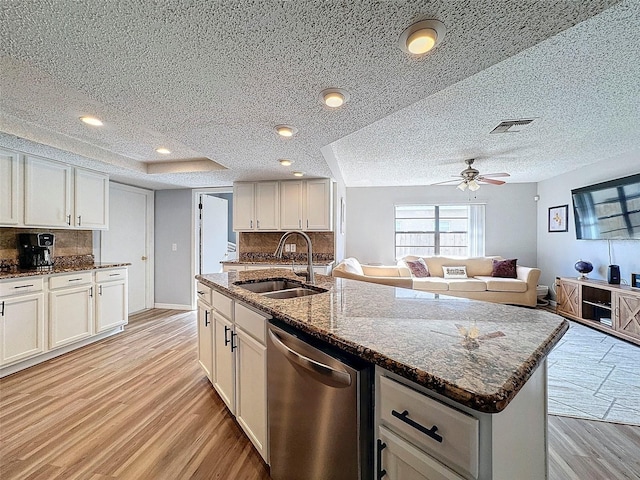 kitchen with stainless steel dishwasher, white cabinets, decorative backsplash, and sink