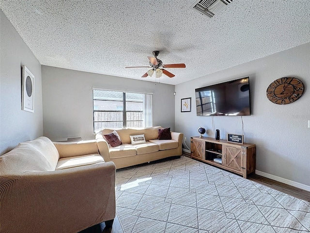 living room with a textured ceiling, ceiling fan, and light wood-type flooring