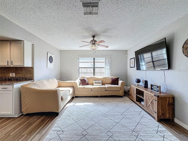 living room featuring a textured ceiling, ceiling fan, and light hardwood / wood-style floors