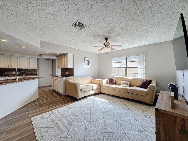 unfurnished living room with light wood-type flooring, ceiling fan, a textured ceiling, and sink