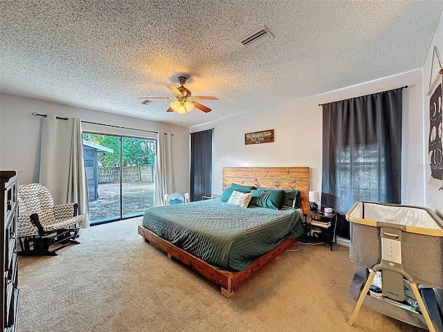 carpeted bedroom featuring access to outside, a textured ceiling, and ceiling fan