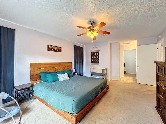 bedroom with a textured ceiling, ceiling fan, and light colored carpet