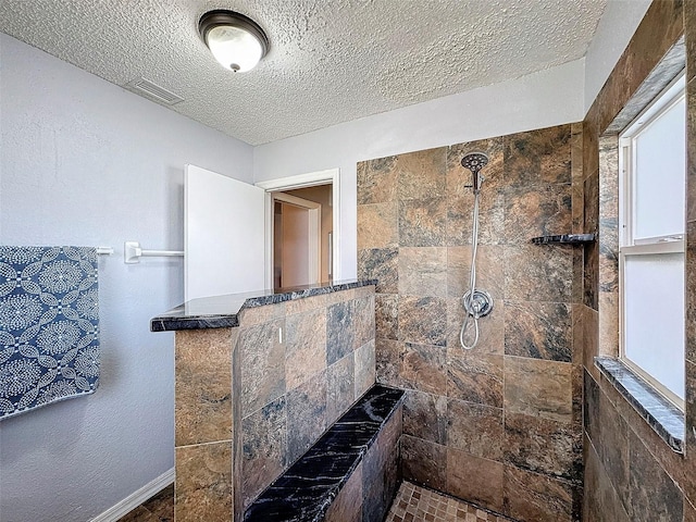 bathroom featuring a textured ceiling and tiled shower