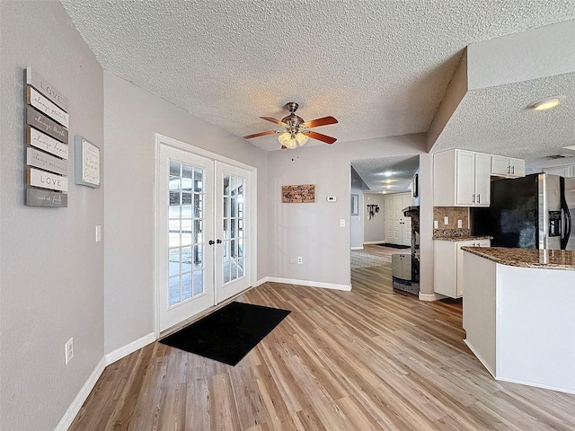 kitchen featuring ceiling fan, stainless steel fridge, french doors, decorative backsplash, and white cabinets