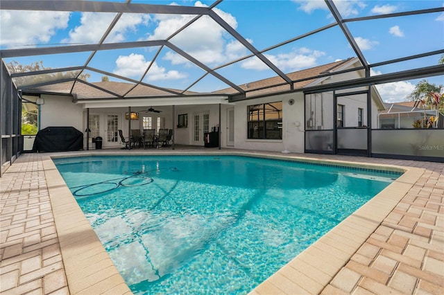 view of swimming pool with ceiling fan, a patio area, glass enclosure, and french doors