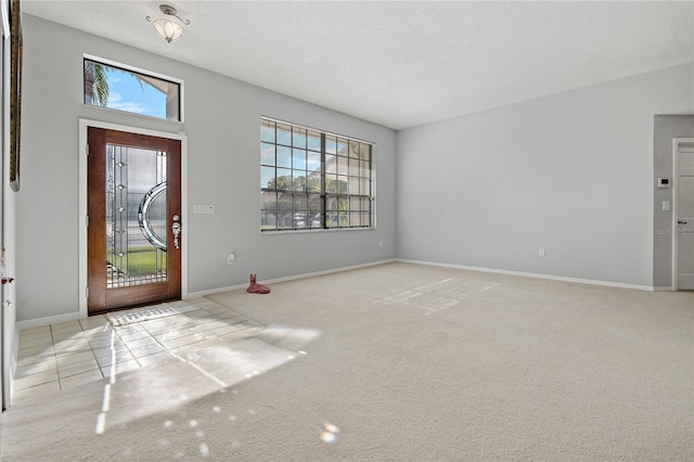 foyer entrance featuring light carpet and a textured ceiling