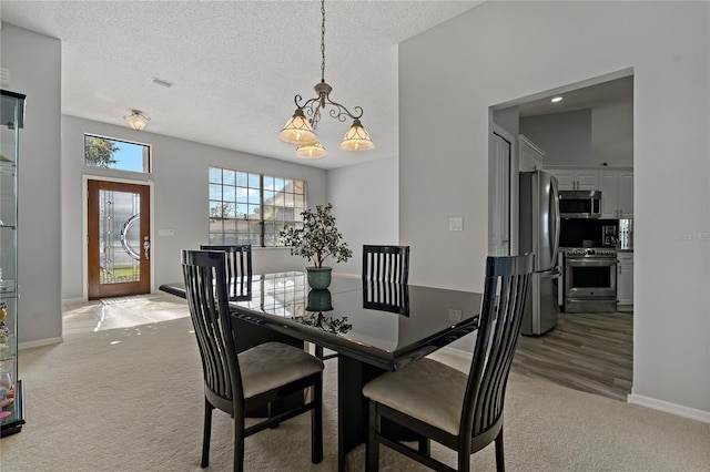 dining area with a textured ceiling, light carpet, and a notable chandelier