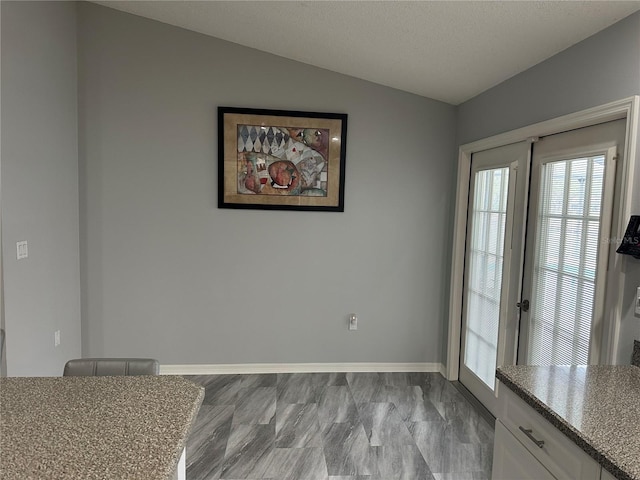 unfurnished dining area featuring lofted ceiling and a textured ceiling