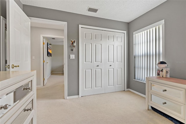 bedroom featuring light colored carpet, a textured ceiling, and a closet