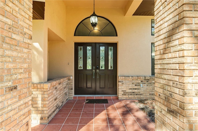 7443 Oak Tree Ln, Spring Hill, FL 34607 - view of exterior entry featuring stucco siding, brick siding, french doors, and a porch