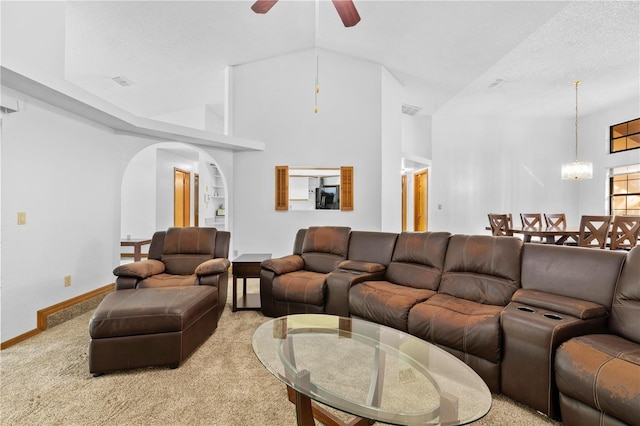 carpeted living room with a textured ceiling, ceiling fan with notable chandelier, and high vaulted ceiling