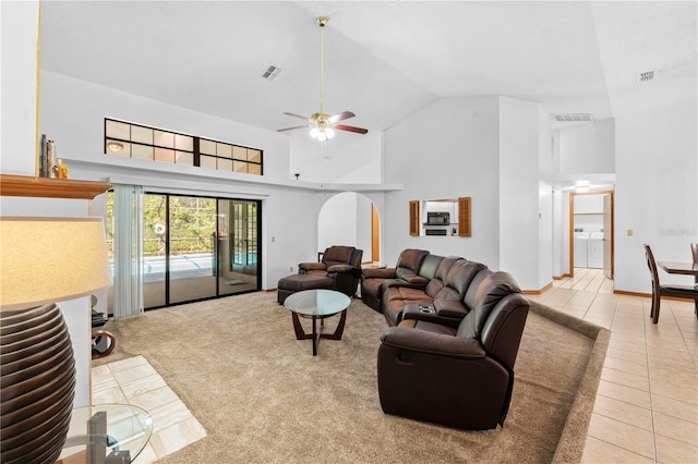 tiled living room with washing machine and clothes dryer, ceiling fan, and high vaulted ceiling