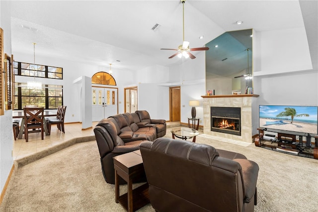 tiled living room featuring ceiling fan, a fireplace, and high vaulted ceiling