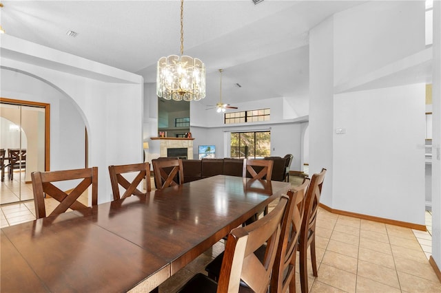 tiled dining area with ceiling fan with notable chandelier and high vaulted ceiling