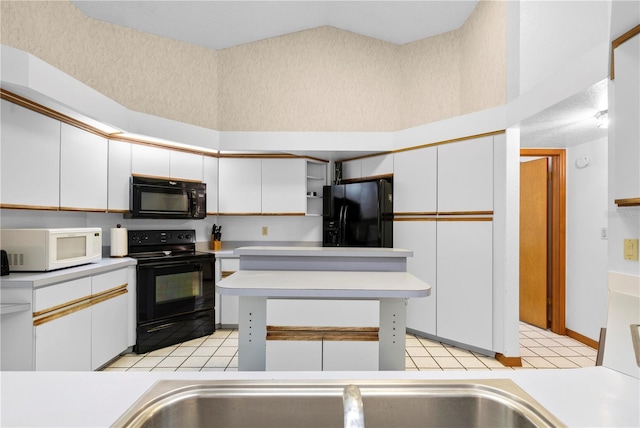 kitchen featuring vaulted ceiling, white cabinets, black appliances, and light tile patterned floors