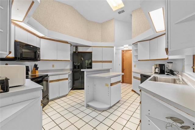 kitchen with white cabinetry, sink, light tile patterned floors, and black appliances