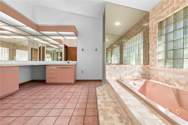 bathroom featuring tile patterned flooring, vanity, and tiled bath