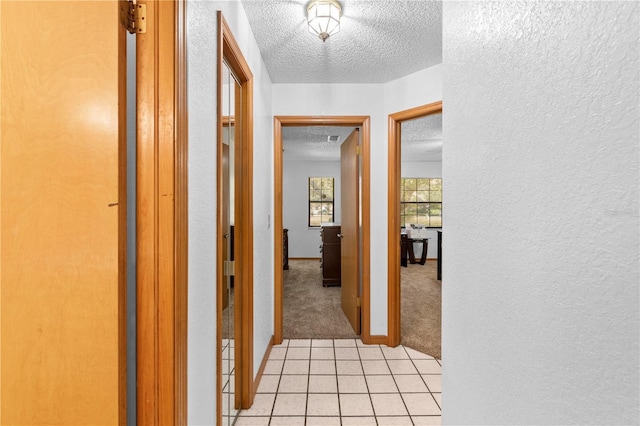 hall featuring light colored carpet and a textured ceiling